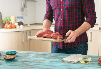 Wall Mural - Man cooking meat on wooden table in the home kitchen