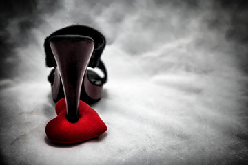 women shoes stomp on broken heart in dark tone., unrequited love., love concept for valentines day.