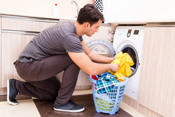 Wall Mural - Young husband man doing laundry at home