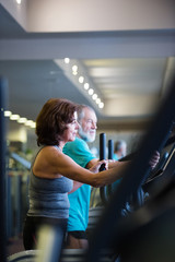 Wall Mural - Beautiful fit senior couple in gym doing cardio work out.