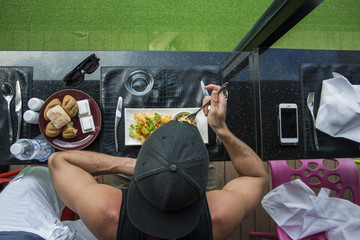 Wall Mural - Handsome young man having meal in cafe or diner, overhead perspective. Seen from above