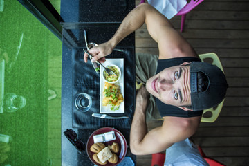 Wall Mural - Handsome young man having meal in cafe or diner, overhead perspective. Seen from above