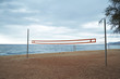 © BublikHaus - Landscape view on empty morning beach with volleyball grid stretched between two steel poles, dramatic cloudy sky and blue sea behind