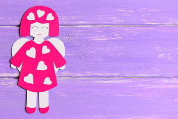 Wall Mural - Angel doll with hearts made of cardboard. Cute angel on lilac wooden background with copy space for text. Valentine's day background. Top view