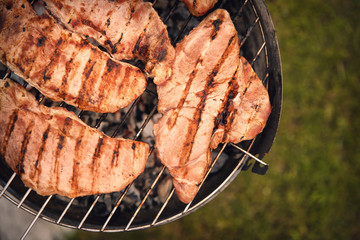 Poster - Tasty steaks on barbecue grill against blurred background, close up view