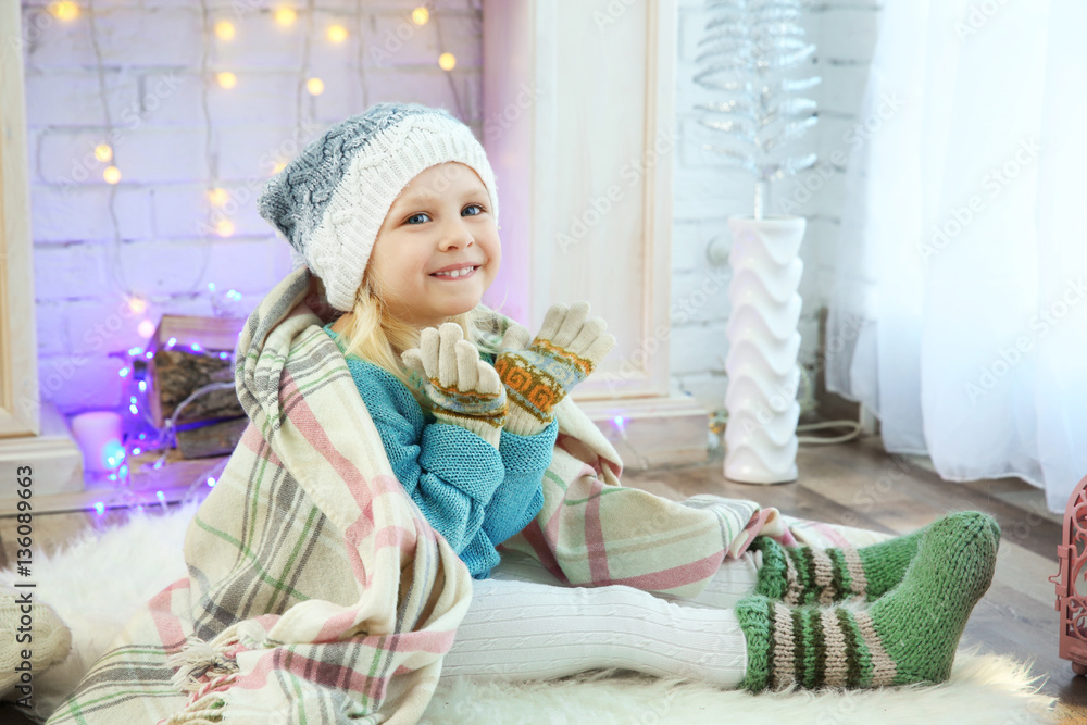 Cute little girl sitting on floor at home