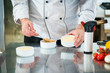 Koch oder Patissier bereitet eine Creme Brulee vor und streut Zucker darauf
