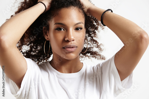 serious black woman touches her hair and watching at camera Slika na platnu