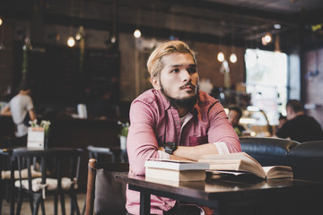 Wall Mural - Hipster bearded man reading book in cafe.