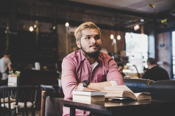 Wall Mural - Hipster bearded man reading book in cafe.