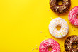 Flat lay donuts on a yellow background with copy space. Top view