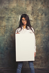 Beautiful girl smiling and posing in white business shirt and blue jeans with a white canvas. Horizontal mockup