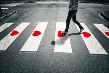Person Crossing With Painted Red Heart Shapes On The Asphalt Floor.