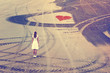 © robsonphoto - Woman in white dress stand alone on the sandy beach with red heart symbol and wheel trace curves. Vintage filter effect used.