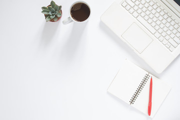 Overhead view of working desk with white laptop computer, cup of