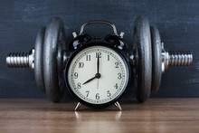 Barbell On A Gray Background And Retro Alarm Clock. Time 8:00