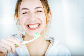 Happy young woman brushing teeth .