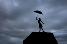Silhouette Of A Girl With An Umbrella At Sunset Jumping