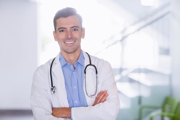 Wall Mural - Portrait of smiling doctor standing with arms crossed