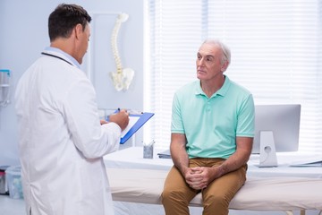 Doctor writing on clipboard in clinic