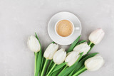 Fototapeta Tulipany - Coffee mug with spring tulip flowers for good morning on gray stone table top view in flat lay style. Breakfast on Mothers or Womens day.