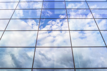 Modern Glass Front Of Building Reflecting Clouds And Blue Skies.