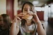 © Cavan Images - Girl eating donut while sitting at home