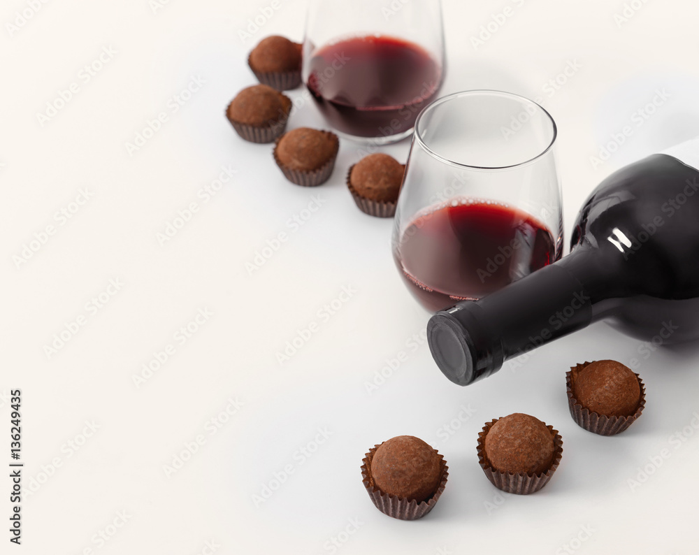 Delicious chocolate truffles and red wine on white background