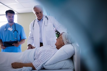 Wall Mural - Doctors comforting senior patient on bed