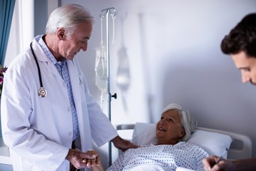 Wall Mural - Doctors comforting senior patient on bed