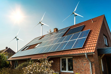 Wall Mural - Solar panel on a roof of a house and wind turbins arround - concept of sustainable resources