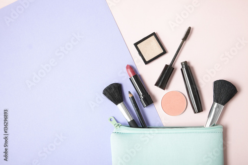 Fotografie, Obraz Make up products spilling out of a pastel blue cosmetics bag, on a pink and purp