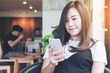 © Farknot Architect - Beautiful Asian girl with smiley face using smart phone in modern cafe