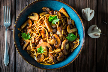 Creamy spaghetti with mushrooms and parsley in blue bowl