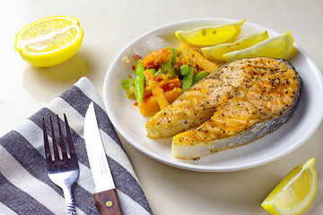 Grilled salmon on white plate with lemon slices