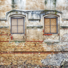 abandoned grunge cracked stucco wall with two window grilles