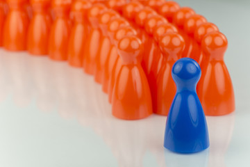 Conceptual orange game pawns and a blue play pawn