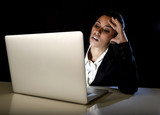 Fototapeta Tulipany - young business woman or student girl working in darkness on laptop computer late at night tired