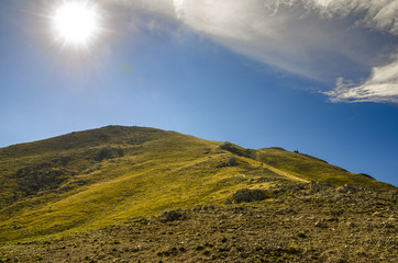 Paesaggio di montagna durante la stagione estiva con sole alto nel cielo
