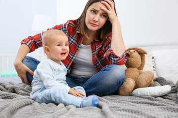 Depressed young woman with cute baby at home