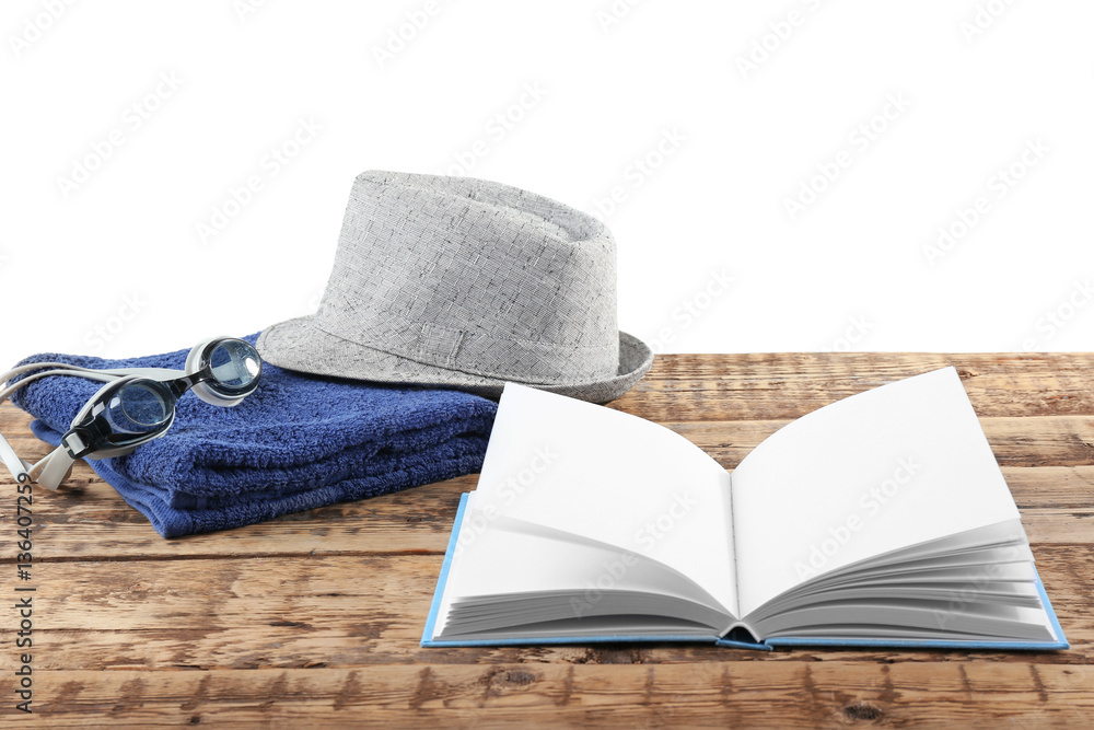 Opened book, hat and towel on wooden table