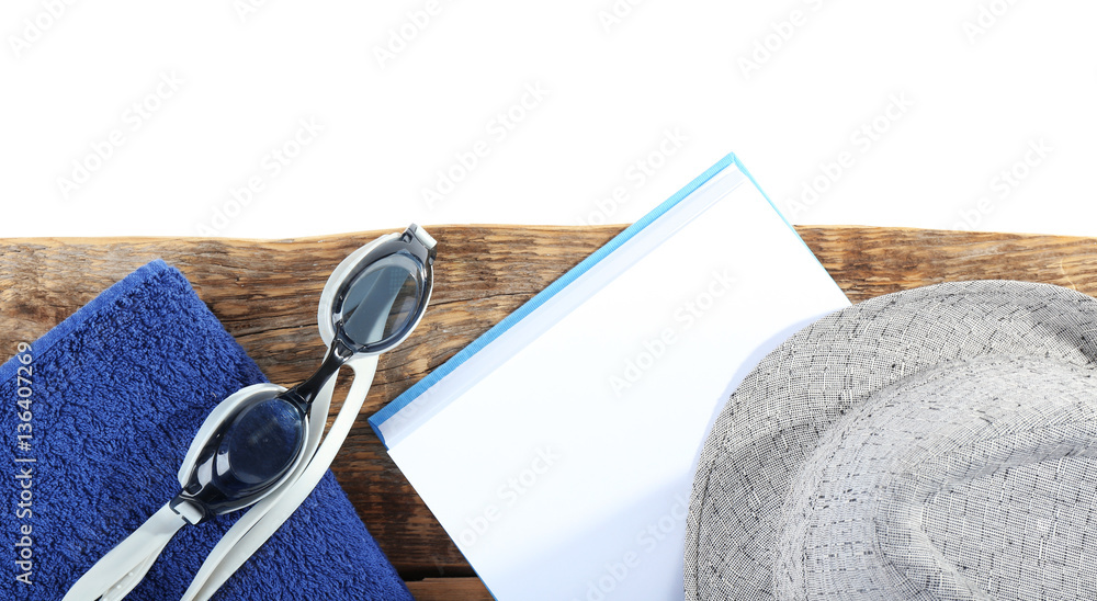 Opened book, hat and towel on wooden table