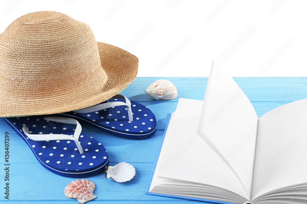 Vacation concept. Book, flip-flops and hat on blue wooden table