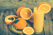 Squeezed orange juice and fresh oranges fruits on rustic wooden table