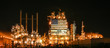 © Cavan Images - American flag on illuminated oil refinery against sky at night
