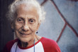© Cavan Images - Portrait of a smiling senior woman standing against wall