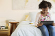 © Cavan Images - Girl using tablet computer while sitting on bed