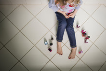 High Angle View Of Girl With Various Nail Polish Bottles Sitting On Floor At Home