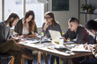 © Cavan Images - College students studying while sitting at table by window in classroom