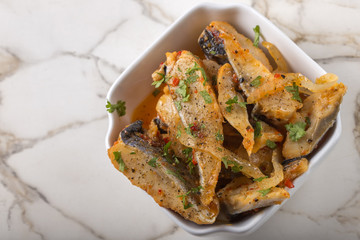 Marinated herring fish with onion and tomato sauce in white bowl